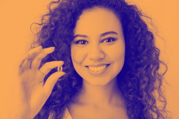 orange washed image of female holding pill in hand